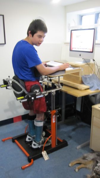 Jon in his stander with his computer on boxes at his height