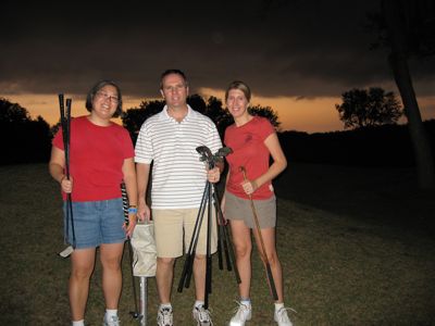 Laura, Patti and David at dusk holding golf clubs